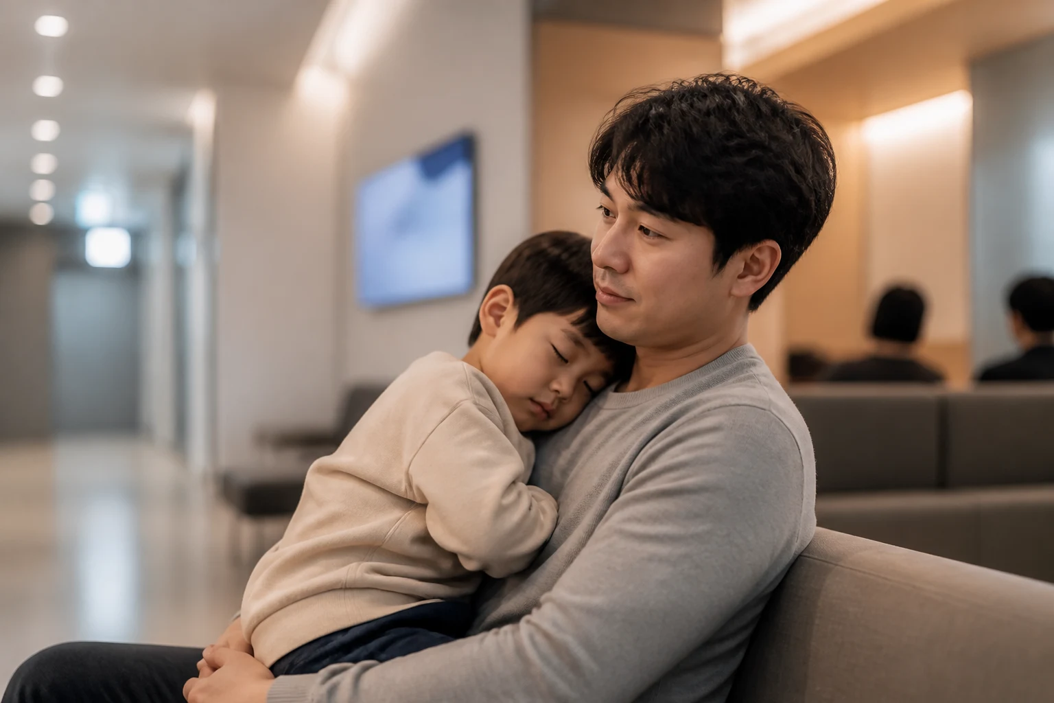 밤에 아이를 안고 병원 대기석에 앉아 있는 부모
